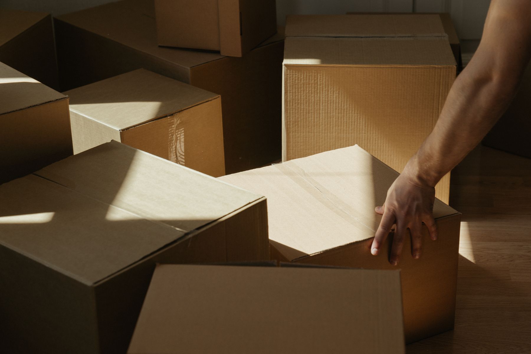 A person carefully moving packed household boxes